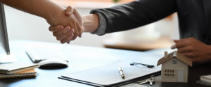 Two people shaking hands over a real estate contract