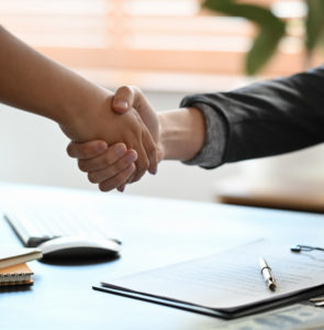 Two people shaking hands over a real estate contract